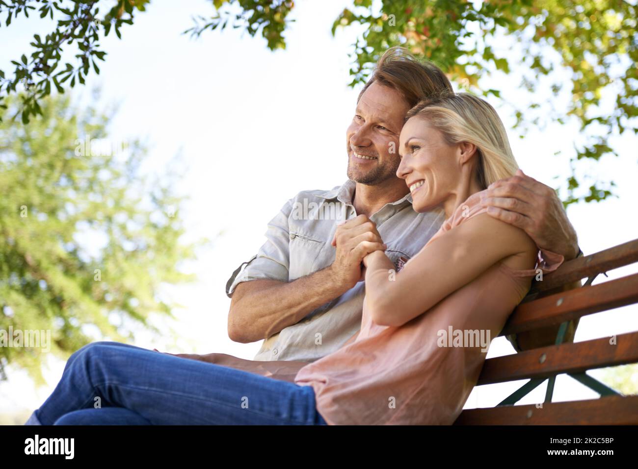 Love is inspired by the simplicity of nature. Shot of a happy mature couple sitting on a bench in the park. Stock Photo