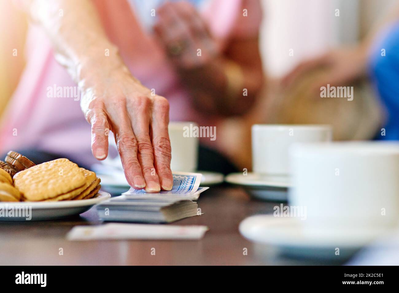 Taking one from the deck. Cropped shot of seniors playing cards in their retirement home. Stock Photo