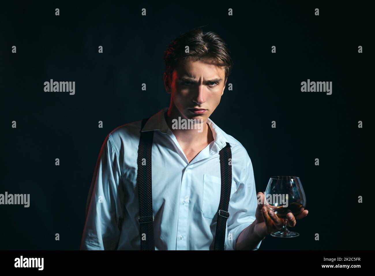 Elegant and stylish man in classical wear with wiskey. Stylish rich young man holding a glass of old whisky. Stock Photo