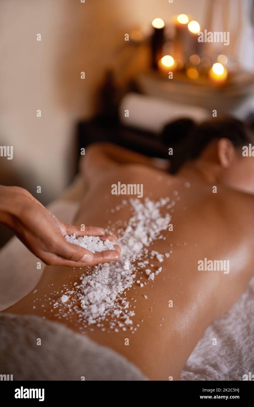 They made it crystal clear that this was spa day. Shot of a young woman enjoying a salt exfoliation treatment at a spa. Stock Photo