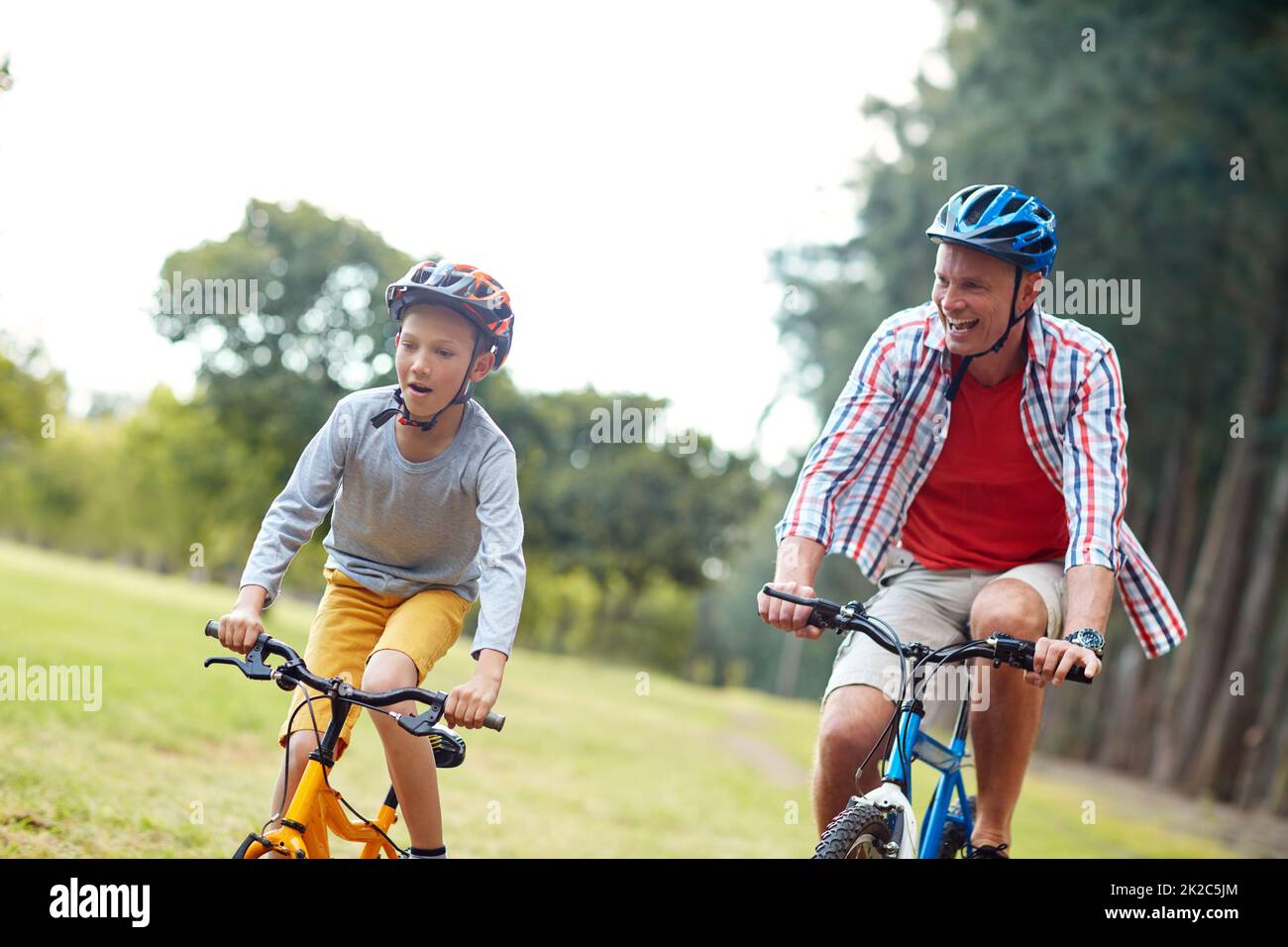 They love racing each other. Shot of a father and son riding bicycles in a park. Stock Photo