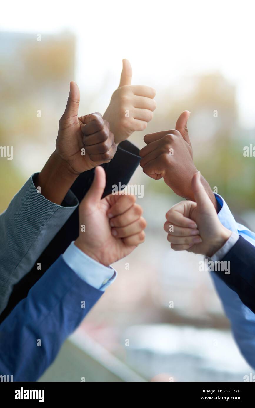 We did it. Shot of a group of unrecognizable coworkers high fiving outside the office. Stock Photo