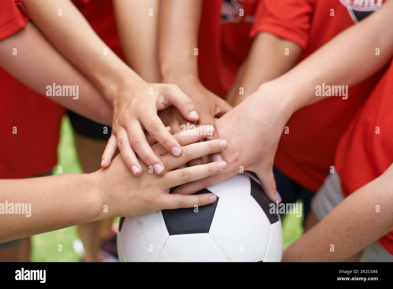 Team spirit. Cropped image of a group of girls with their hands piled on top of a soccer ball. Stock Photo