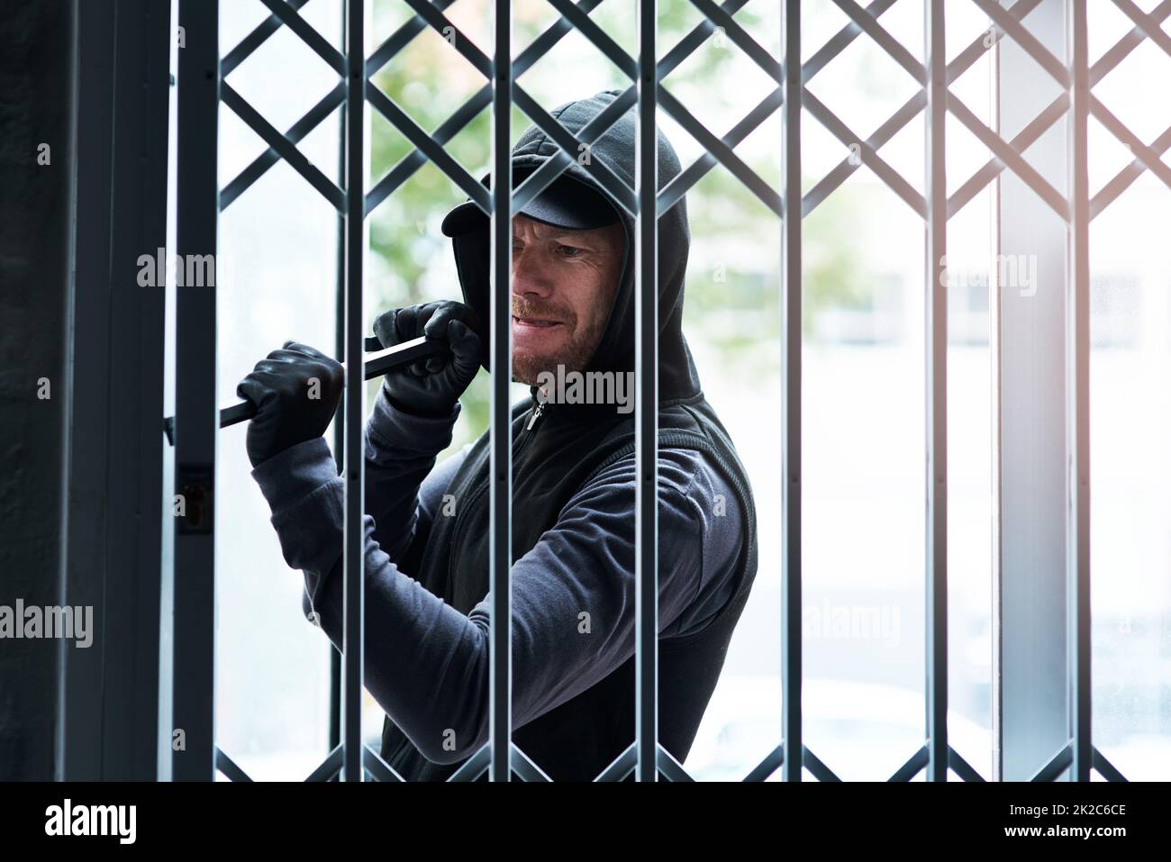 Nothing is going to stop him from breaking inside. Shot of a male burglar using a steel weapon to break into a house. Stock Photo