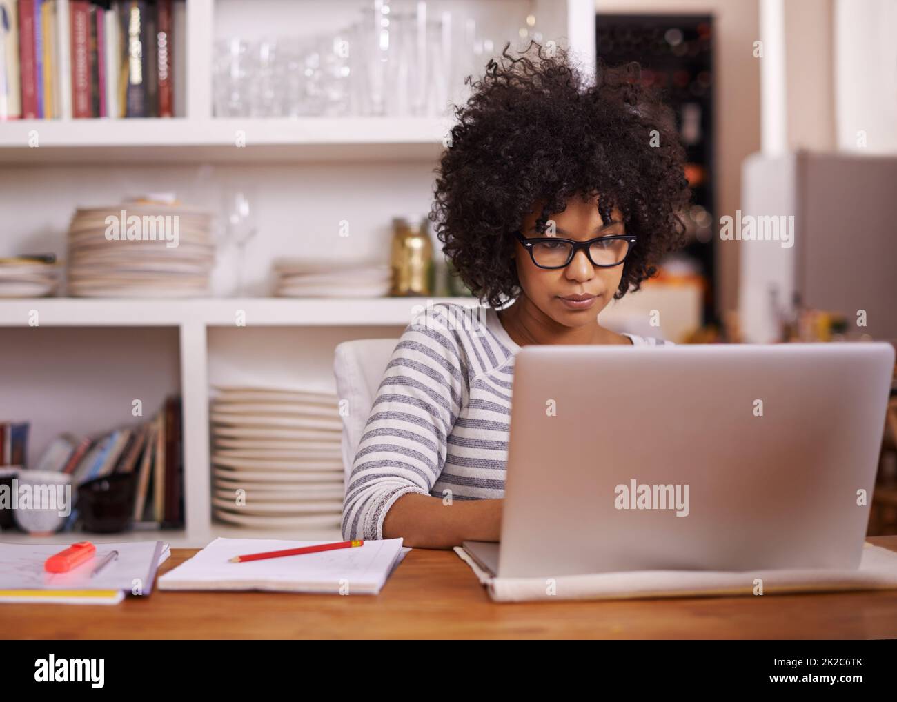 Browsing keeps her busy. Cropped shot of a young woman working on her laptop at home. Stock Photo