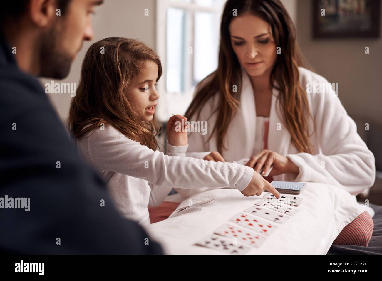 Having fun with mom and dad. Shot of a young family playing cards together at home. Stock Photo
