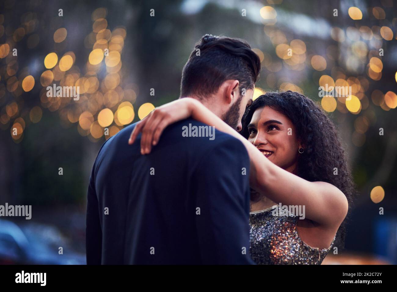 I love being around you. Shot of a cheerful young couple holding one another while looking into each others eyes outside at night. Stock Photo