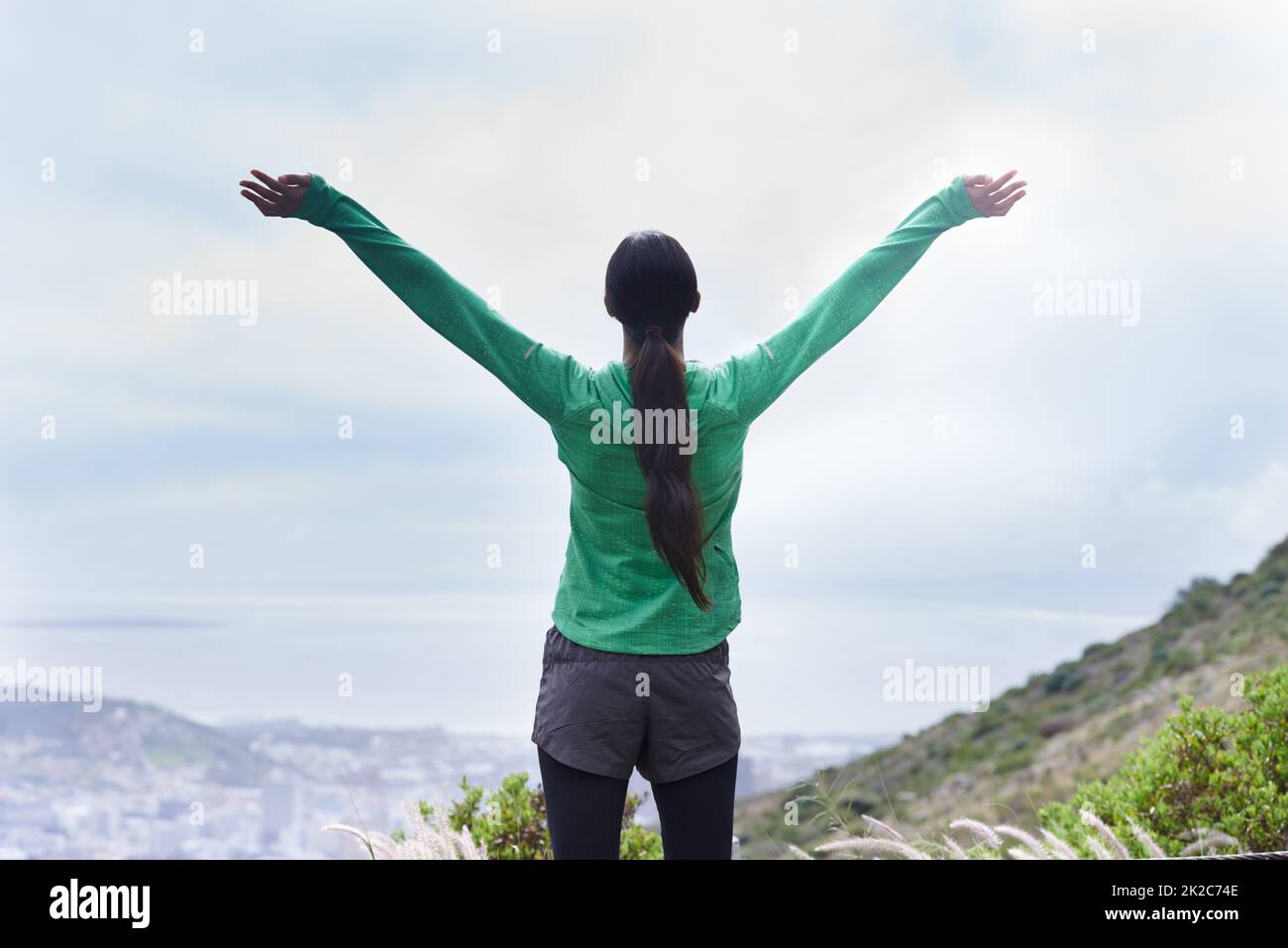Ive reached the peak. Rearview of an adventurous young woman standing with her arms outstretched on the mountain. Stock Photo