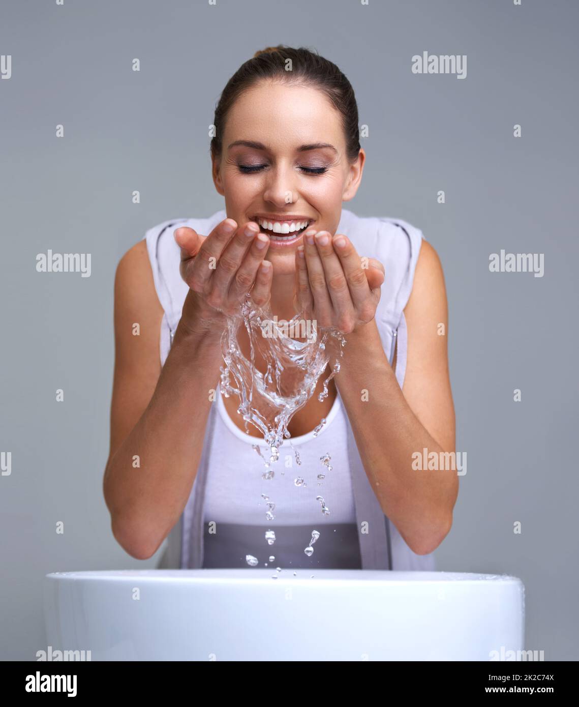 Aah, so refreshing. An attractive young woman washing her face. Stock Photo