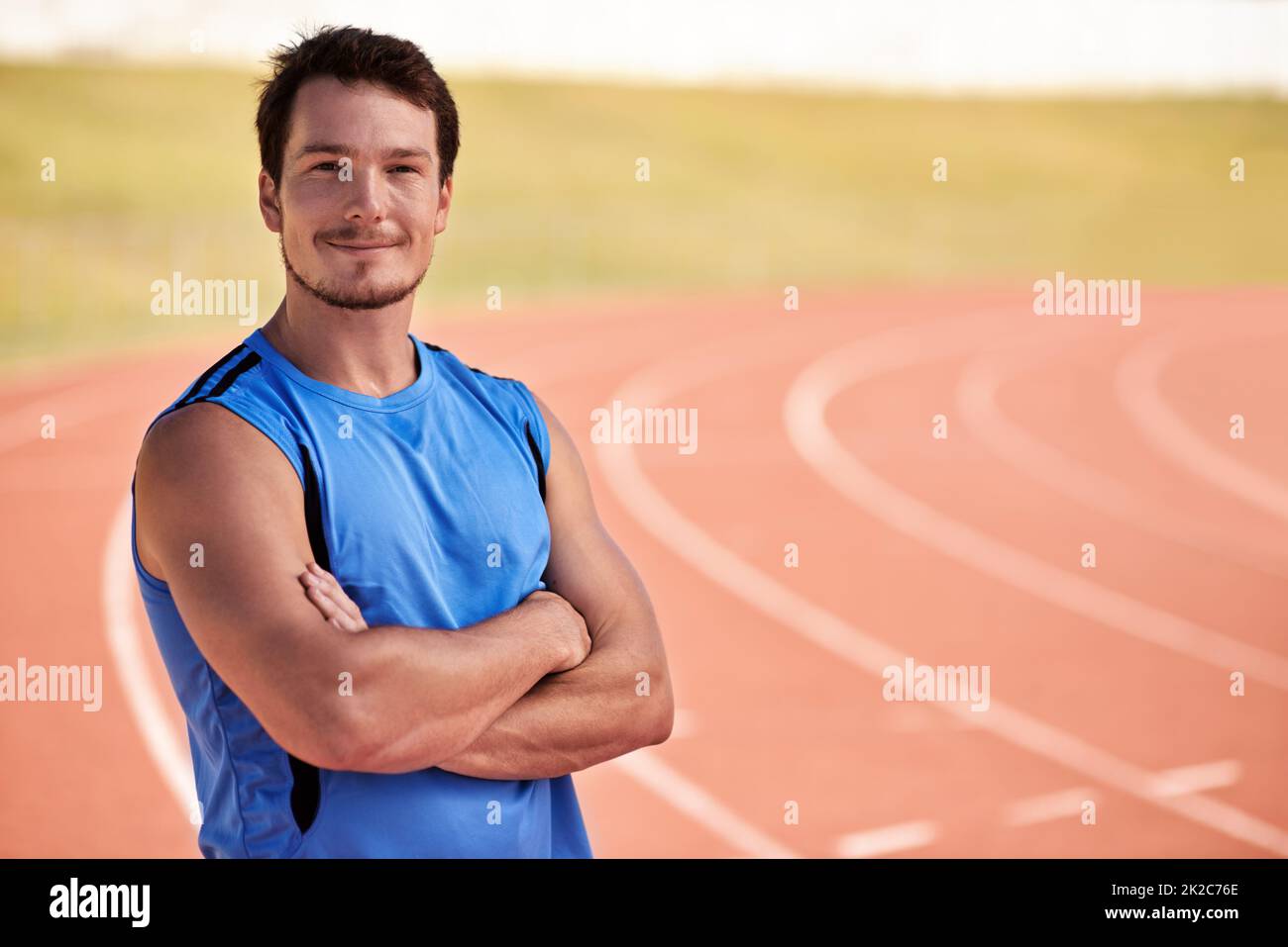 Hes ready to race. Shot of a handsome young runner out on the track. Stock Photo