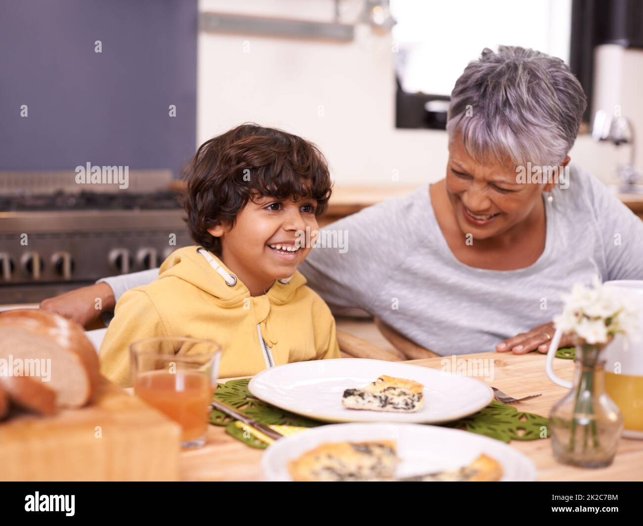 Grannys quiche is the best. A cute little boy eating a meal with his grandmother at home. Stock Photo