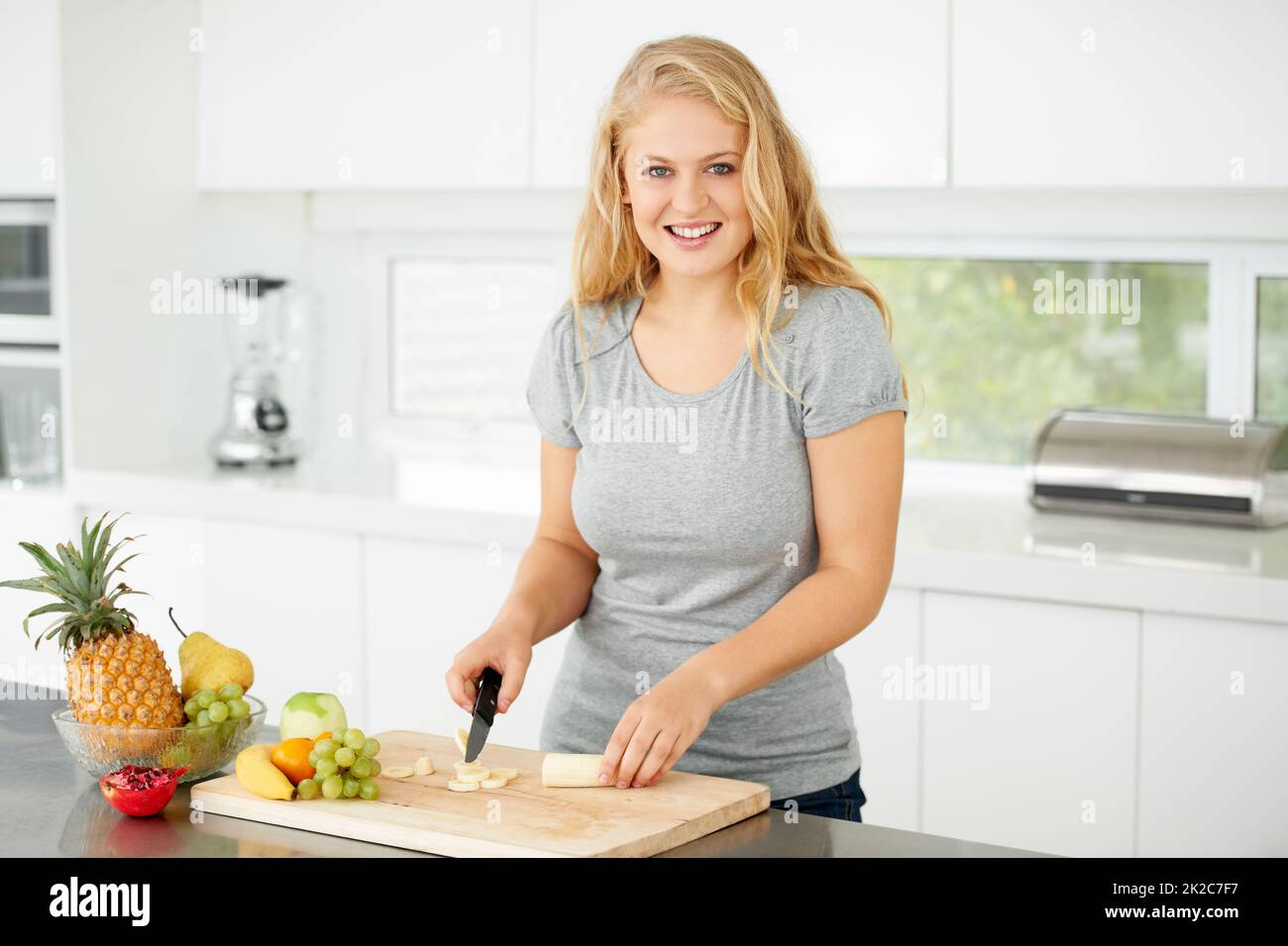 Nothing beats fresh fruit. Attractive curvaceous young woman chopping fruit in her kitchen. Stock Photo