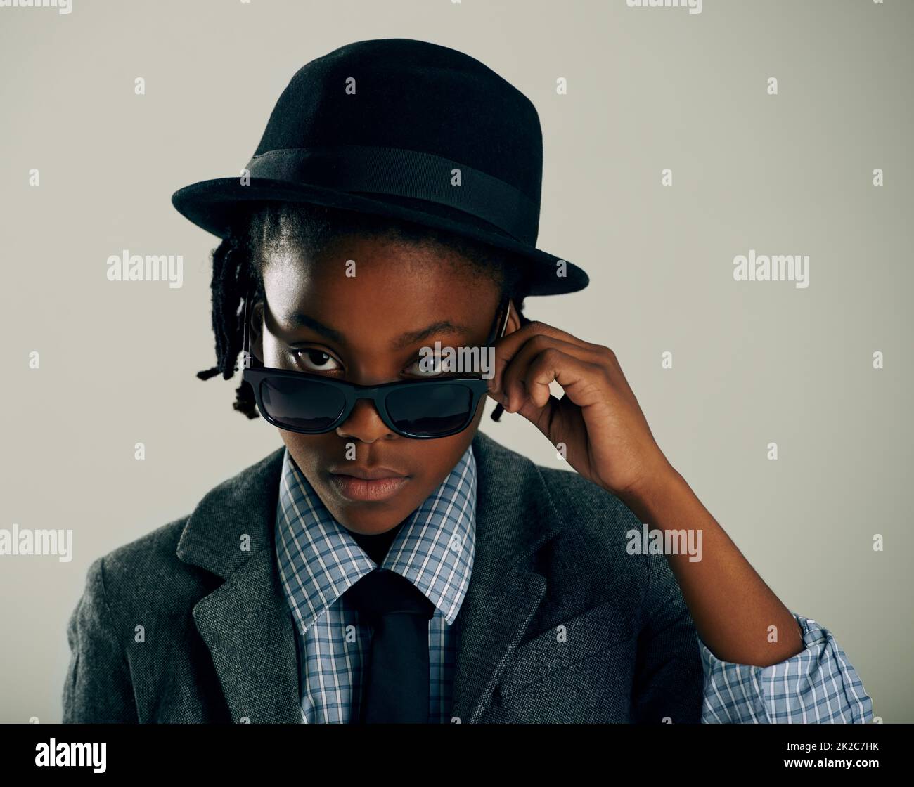 Dressed in his best. Studio shot of a cool ethnic boy peering over his sunglasses. Stock Photo