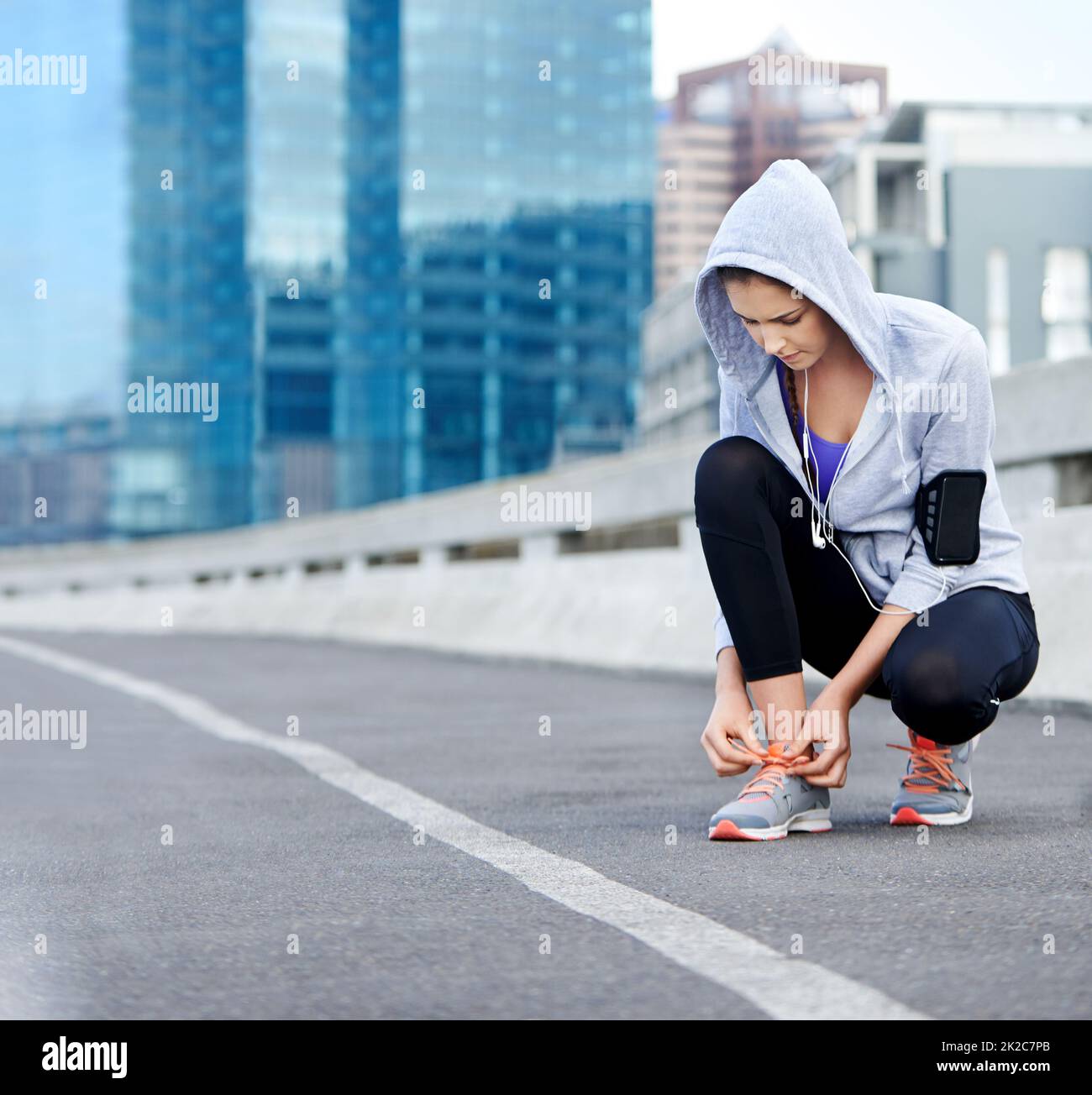 Almost time for these feet to move. Shot of a young female jogger tying up her shoes before a run through the city. Stock Photo