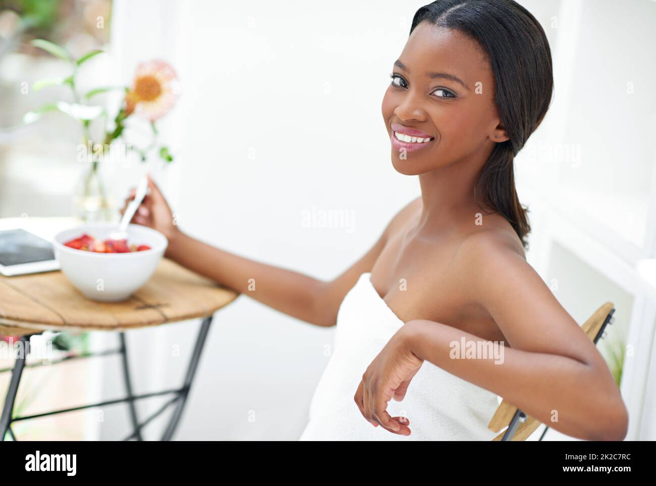 This is the only way to live. Shot of a beautiful young woman eating a bowl of strawberries. Stock Photo