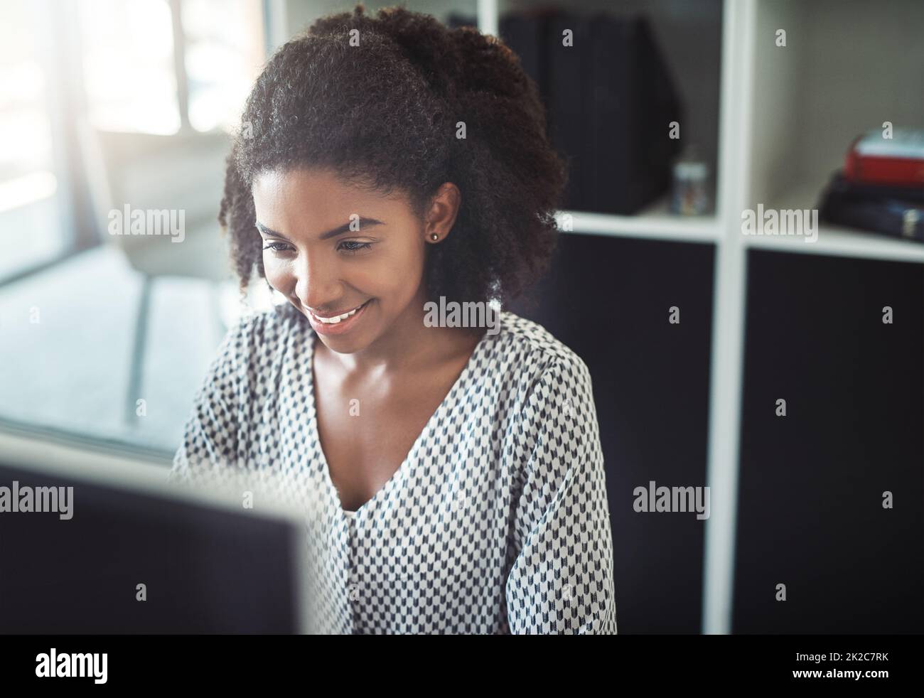 She has a killer work ethic. Cropped shot of a young businesswoman working on her computer at her desk. Stock Photo