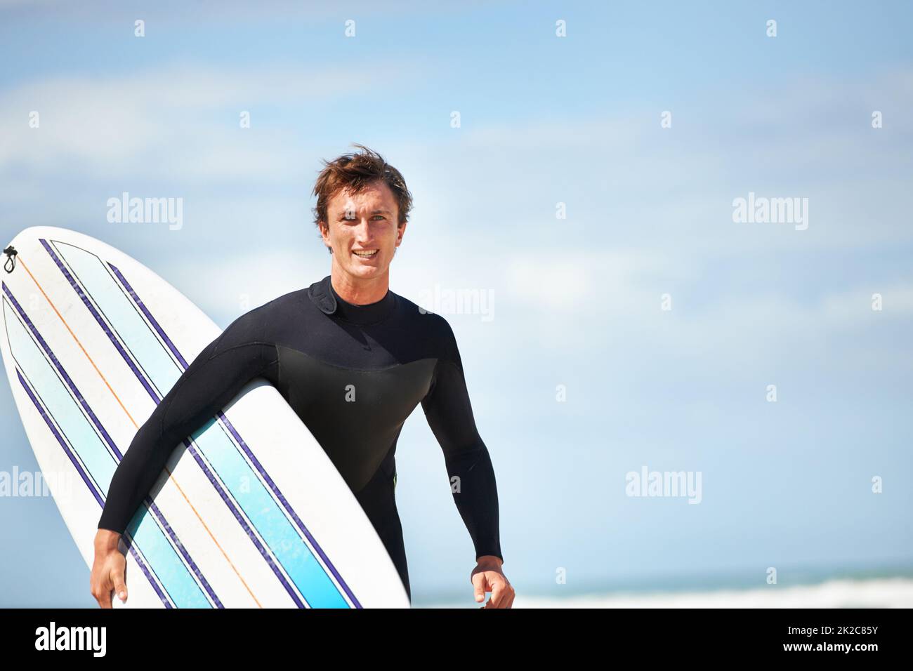 Its just me and my surfboard. Portrait of a young surfer at the beach on a sunny day. Stock Photo