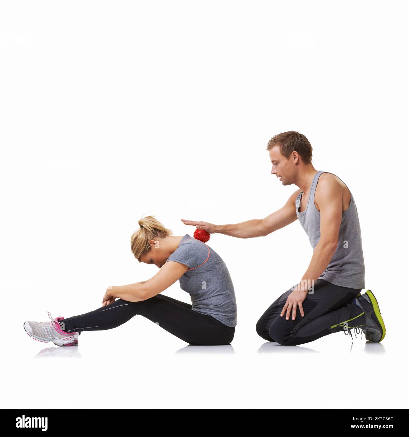 Rolling out her muscles. A young man using a massage ball on his female