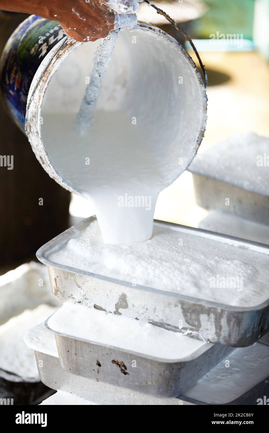 A delicate process. A Thai man pouring liquid rubber into moulds to set. Stock Photo