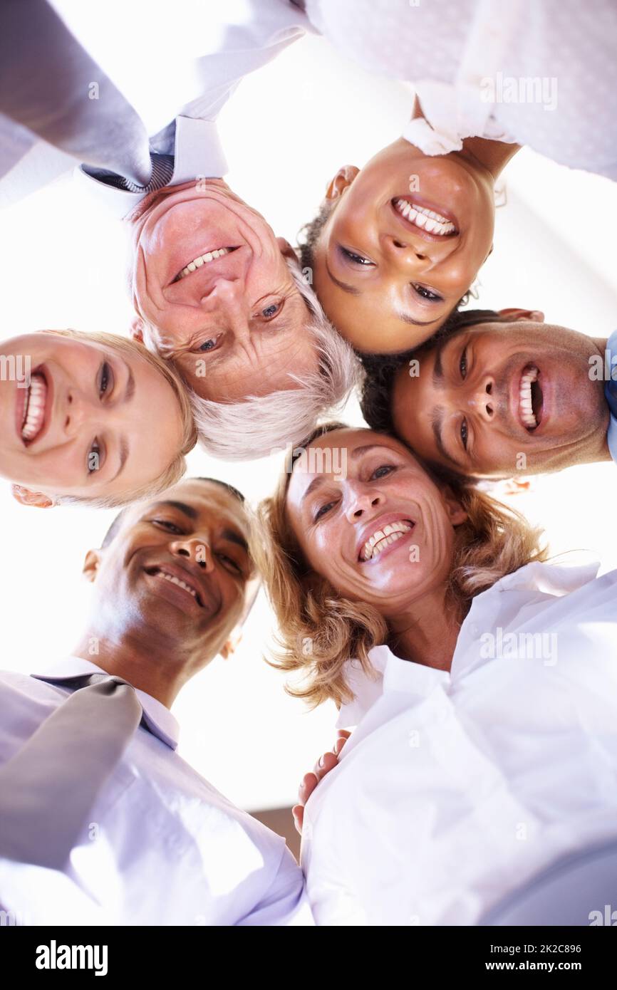 Working towards same goal. Low angle view of multi racial business team in huddle at office. Stock Photo