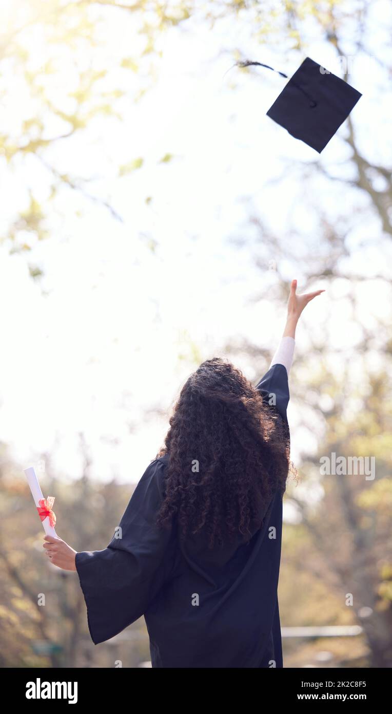 I made it. Rearview shot of a young woman throwing her cap in the air