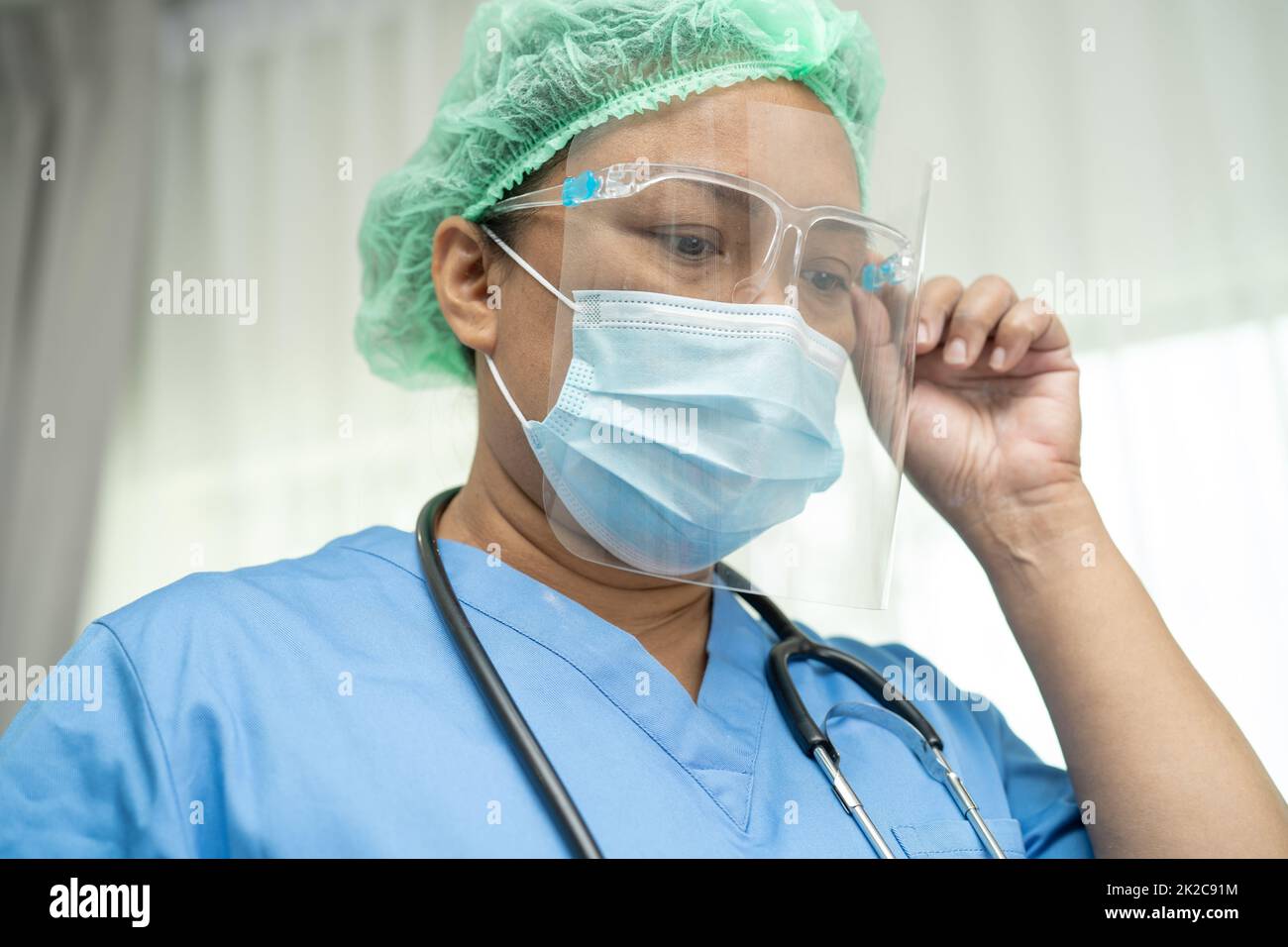 Asian doctor wearing face shield and PPE suit new normal to check patient protect safety infection Covid 19 Coronavirus outbreak at quarantine nursing hospital ward. Stock Photo