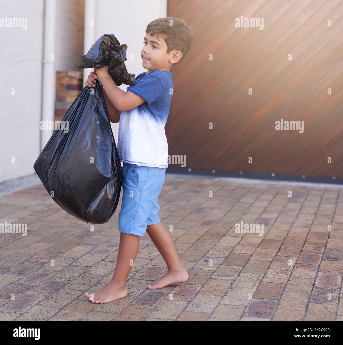 Time to take out the trash. Shot of a little boy taking out the trash at home. Stock Photo