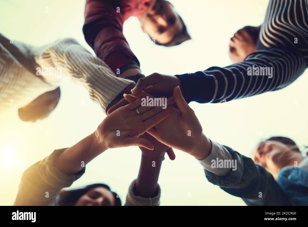 True friends stick together. Low angle shot of a group of students joining their hands in solidarity. Stock Photo