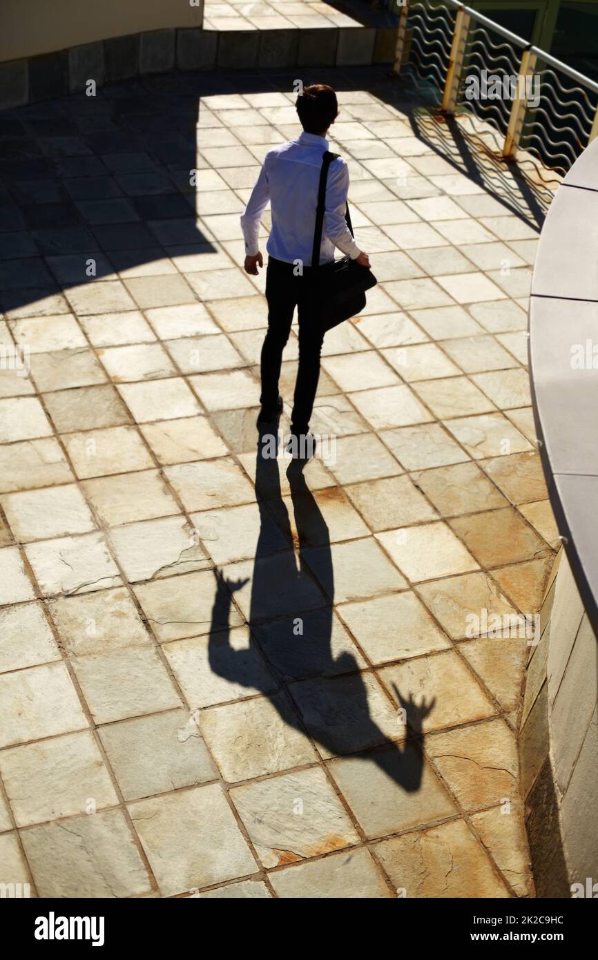 His fear follows him everywhere. Shot of a man being stalked by a ominous shadow of himself. Stock Photo