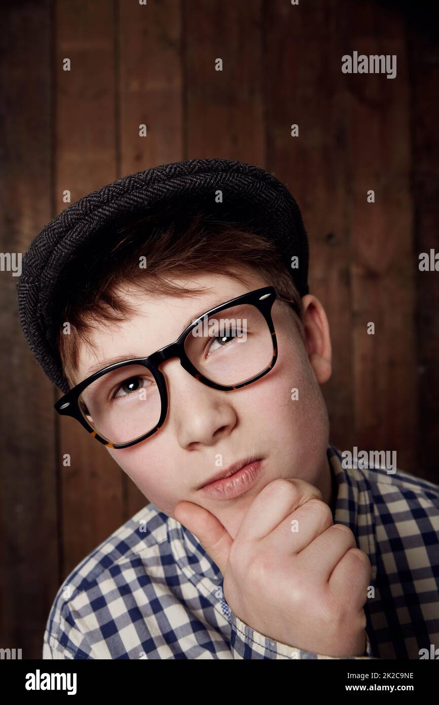 Thinking things through. Young boy in retro clothing wearing spectacles with a thoughtful expression. Stock Photo