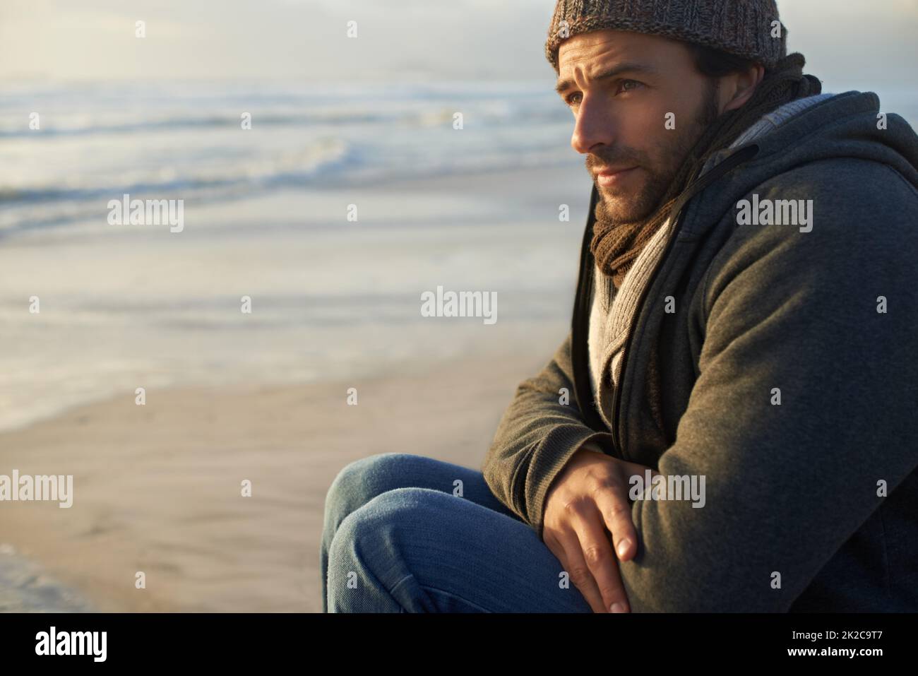 He enjoys being close to the ocean. A handsome young man at the beach. Stock Photo