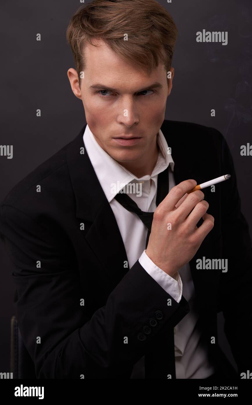 Channeling James Bond. A handsome young man in a suit with a cigarette in his hand. Stock Photo