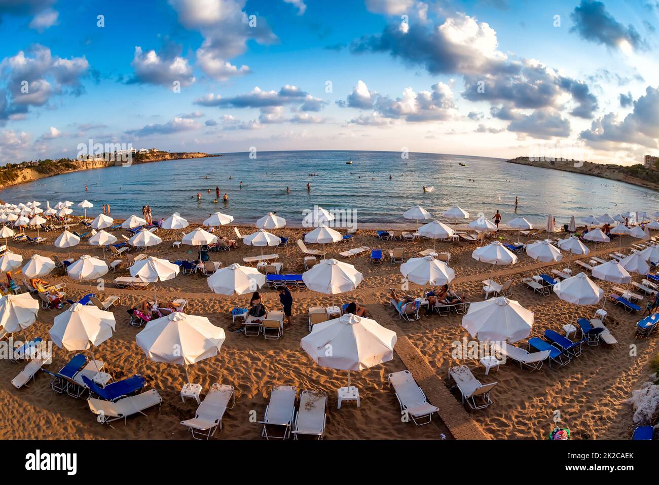 Rows of beach lounges and sun umbrellas on a Coral Bay beach near Peyia village. Stock Photo