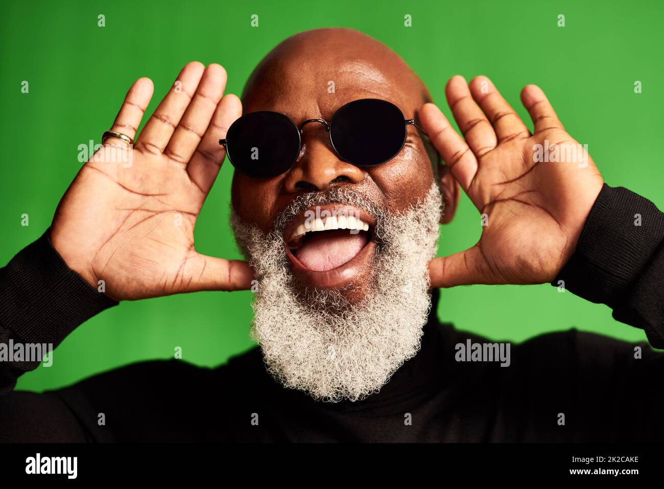 Growing old doesnt mean you have to be boring. Studio shot of a senior man wearing glasses and making funny faces against a green background. Stock Photo