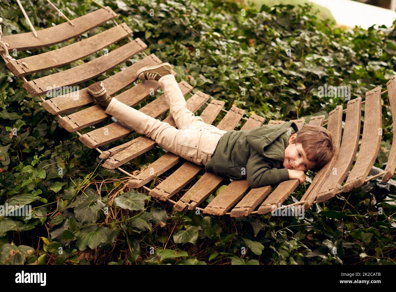 Aaah...the carefree days of childhood....A little boy relaxing in a hammock in his backyard. Stock Photo