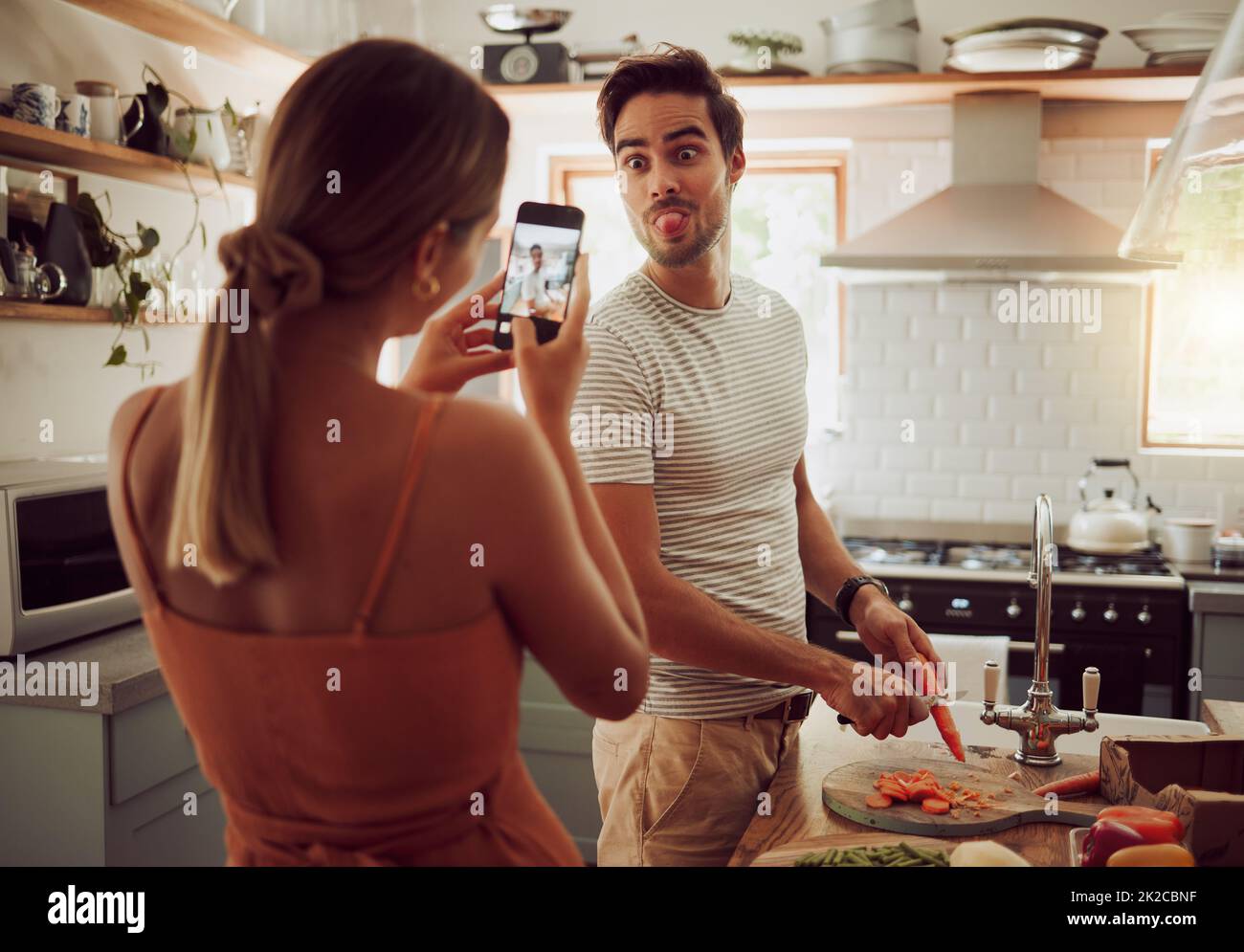 Cooking man sticking out tongue to make silly, goofy and funny face to pose for a photo while making food in the kitchen at home. Crazy, fun and happy Stock Photo