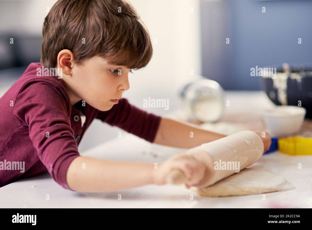 Just roll with it. Shot of a little boy rolling out dough in the kitchen. Stock Photo
