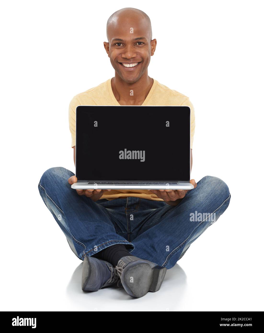 Presenting the future of technology. Studio shot of a smiling African-American man sitting and holding a laptop out in front of him. Stock Photo