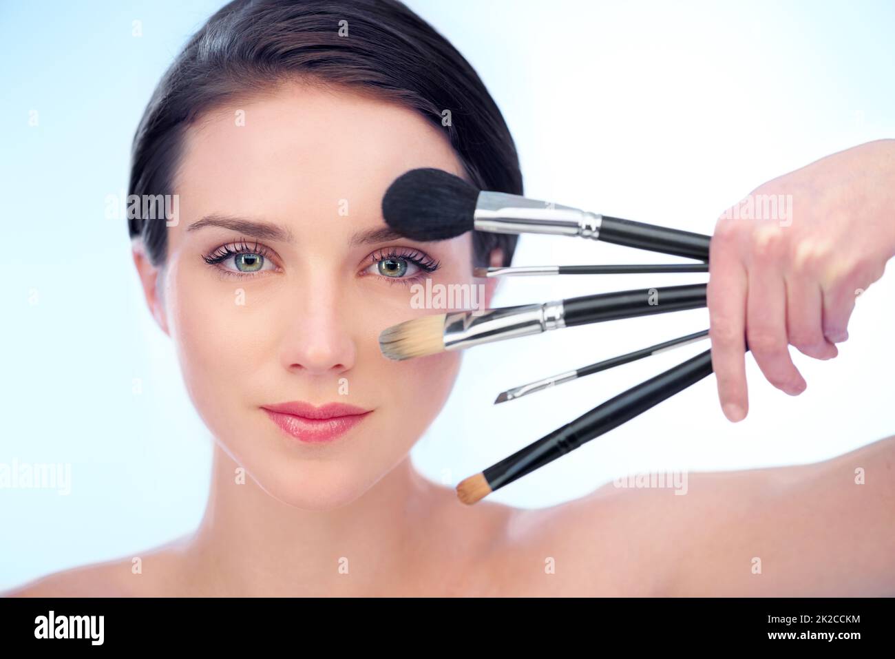 Tools of the beauty trade. A beautiful young woman holding a variety of make-up brushes. Stock Photo