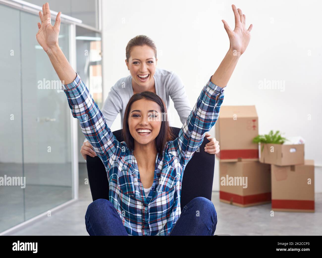 Fooling around in an empty office. Shot of two female entrepreneurs moving into a new office. Stock Photo