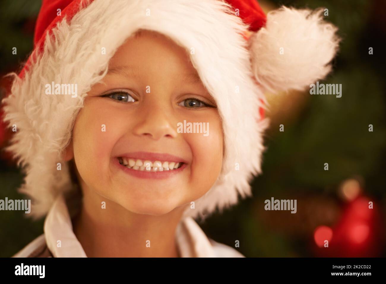 All the presents....I cant wait. Portrait of a young boy wearing a Christmas hat. Stock Photo