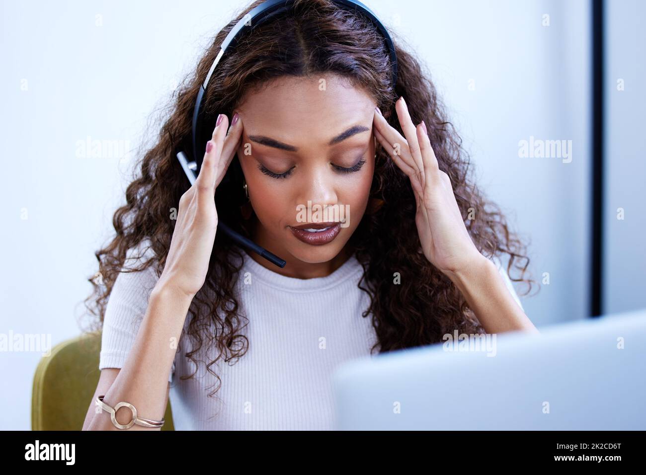 Its been an overwhelming day. Shot of a young call centre agent looking stressed out while working in an office. Stock Photo