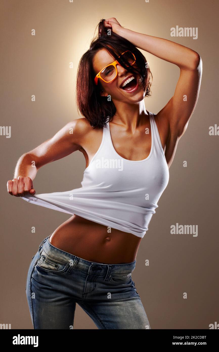 Shes a party girl. Cropped studio shot of an attractive young woman pulling at her tank top. Stock Photo