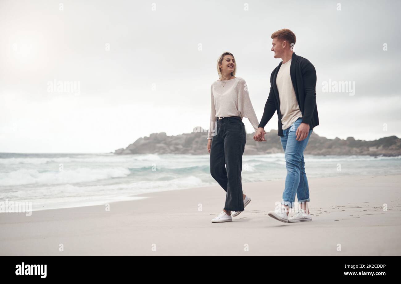 The beach is our favourite place. Shot of a couple holding hands while strolling on the beach. Stock Photo
