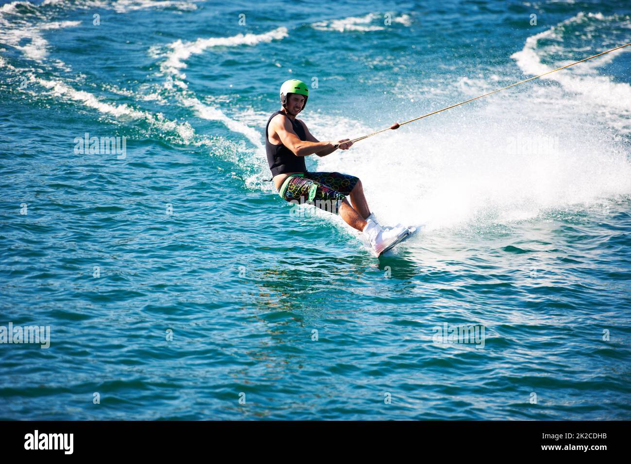 A young man wearing a helmet and lifejacket wakeboarding on a lake Stock Photo Alamy