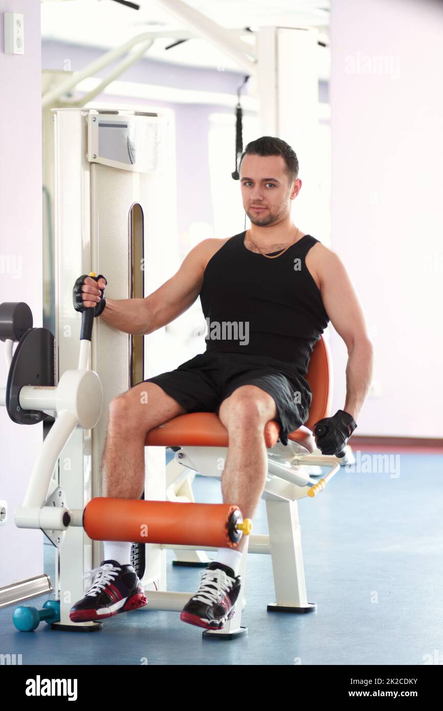 Earn your body. Portrait of a young man using a gym machine to exercise his leg muscles. Stock Photo