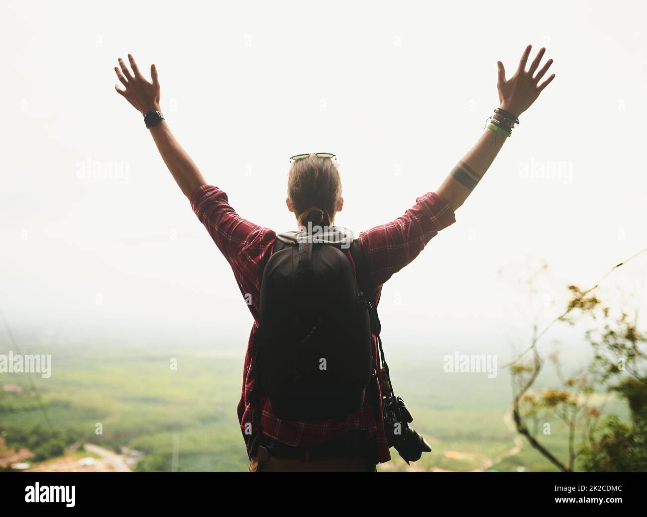 Life is meant to be lived. Rearview shot of a young man standing atop a mountain with his arms outstretched. Stock Photo