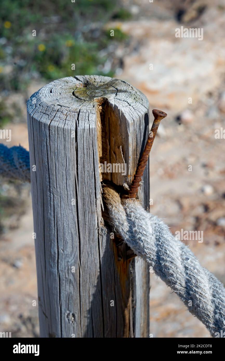 A rope, barrier rope attached to a wooden post, as a path fence Stock