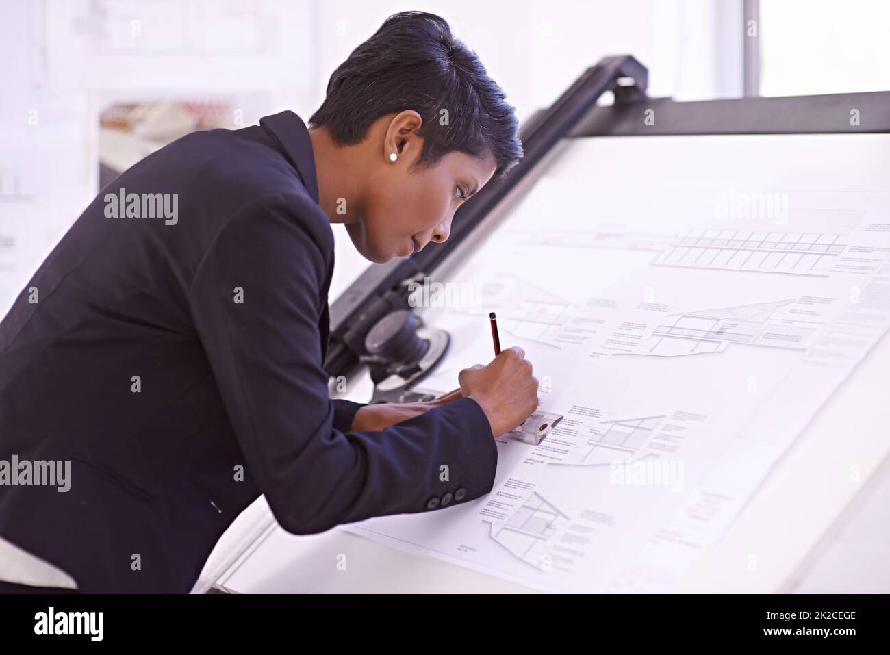 Showing extreme skill at the drawing board. Cropped shot of a female architect working on a building plan at a drawing board. Stock Photo