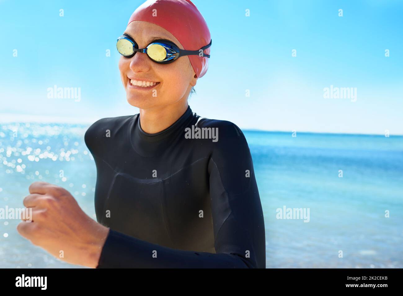 Training to be a lifesaver. A young woman training in a full piece wetsuit and swimming gear on the beach in the winter. Stock Photo